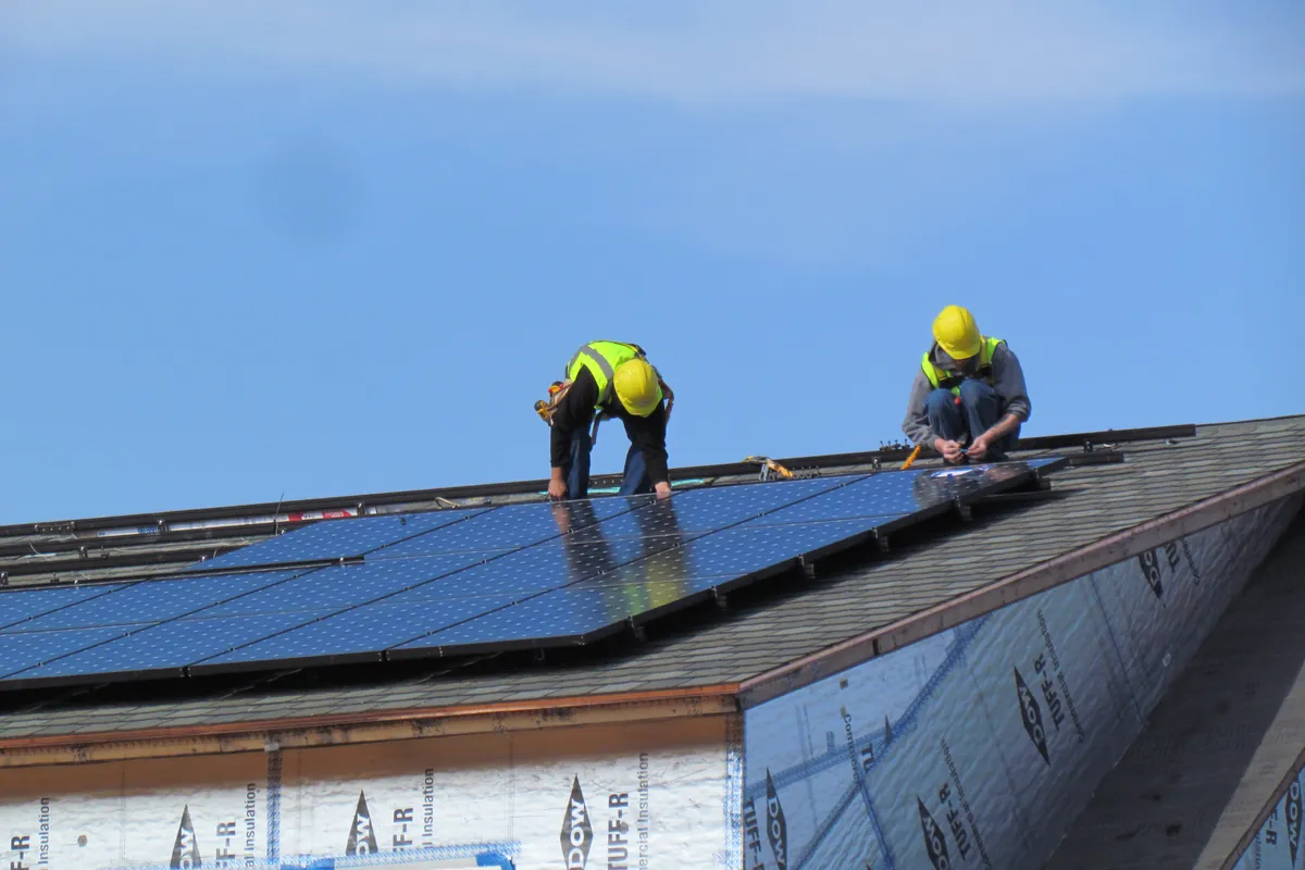 Instaladores fijando un panel en la cubierta