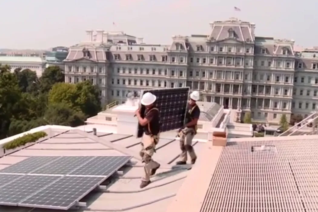 Operarios transportando un panel solar en una cubierta