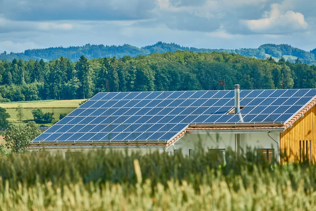 Paneles solares en el jardín de una vivienda con montañas al fondo